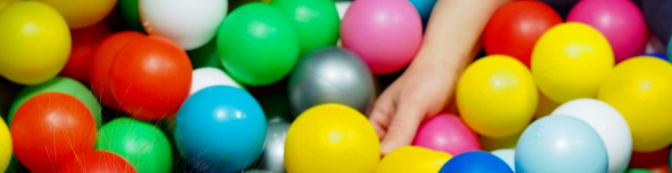 Lapsen käsi värikkäiden pallojen keskellä pallomeressä